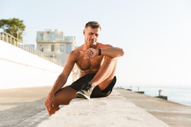 Smiling handsome shirtless sportsman with earphones