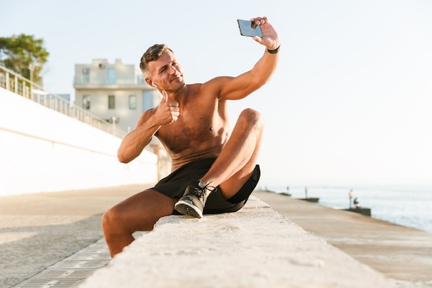 Smiling handsome shirtless sportsman with earphones