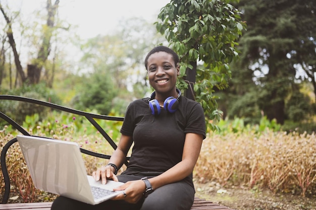 Smiling happy african black shorthaired woman student afro hair with blue headphones studying online