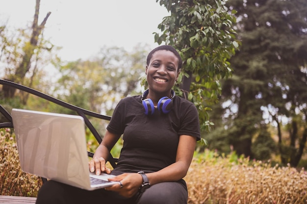 Smiling happy african black shorthaired woman student afro hair with blue headphones studying online