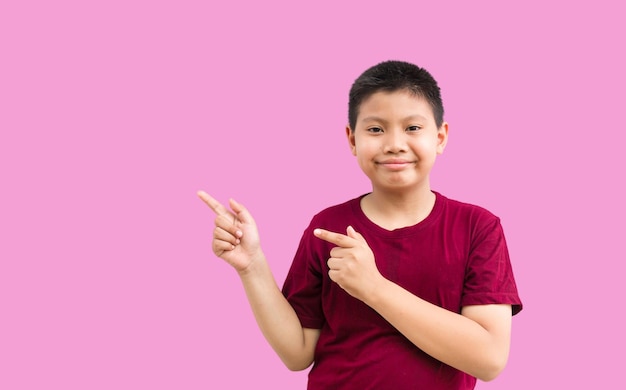 Smiling happy Asian boy pointing his finger away at copy space isolated over a plain background