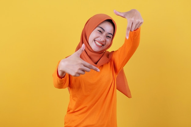 Smiling happy asian woman with close up gesture with yellow background