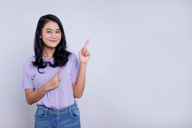 Smiling happy asian woman with her finger pointing isolated on light white banner background with copy space