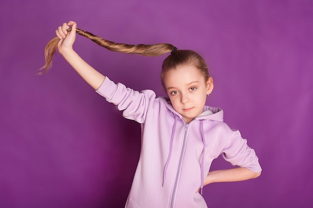 Smiling happy Childhood and the dream of a great and famous future Cute longhaired little girl on a purple studio background Childhood dreams the concept of emotions