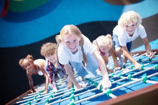 Smiling happy children climbing the ropes while enjoying outdoors activities