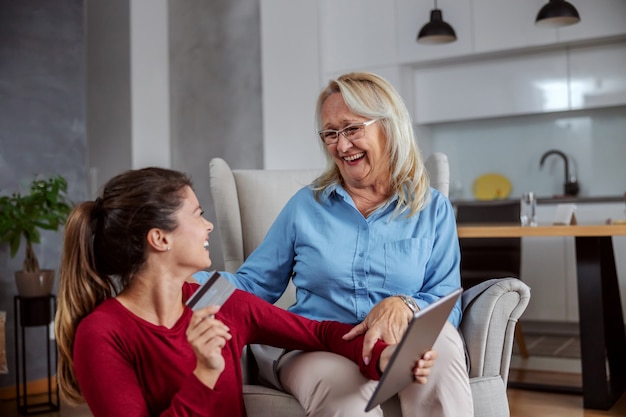 Smiling happy mother and daughter shopping online.