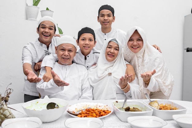 Smiling and happy muslim family showing delicious Eid food dishes with various food at dining room