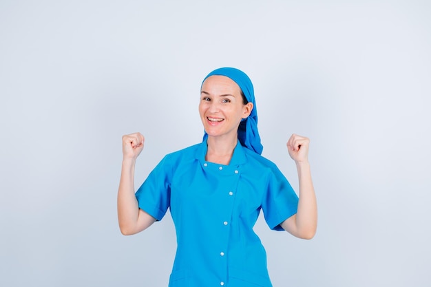 Smiling happy nurse is raising up her fists on white background