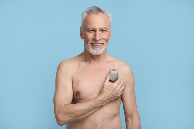 Smiling happy senior man holding a pacemaker on blue background Cardiac surgery Healthcare Medicine