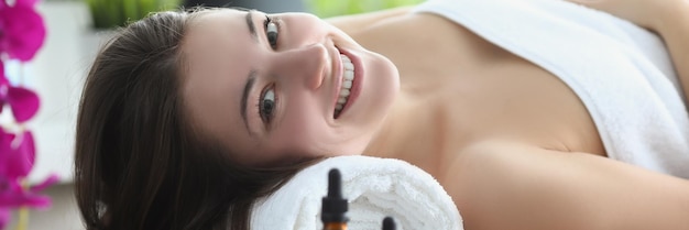 Smiling happy woman laying covered with towels in luxury spa centre