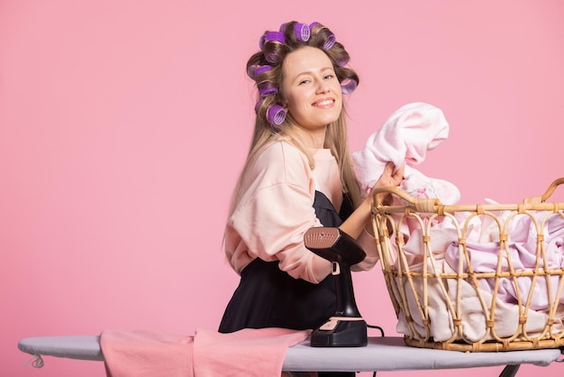 Smiling happy woman in pink background sniffs clean washed laundry smelling of powder