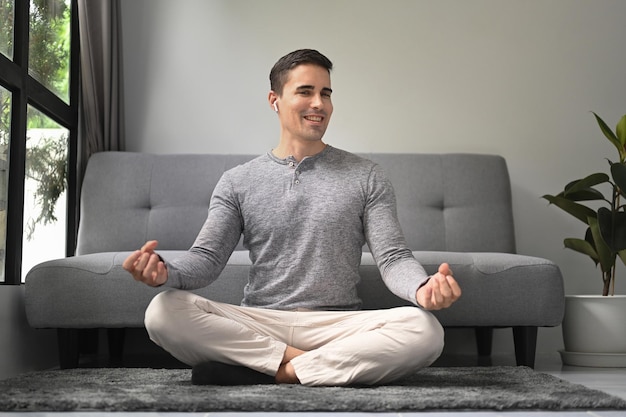 Smiling healthy man practicing yoga at home Meditation and healthy lifestyle concept