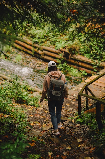 Smiling hiker woman walking by autumn forest road copy space