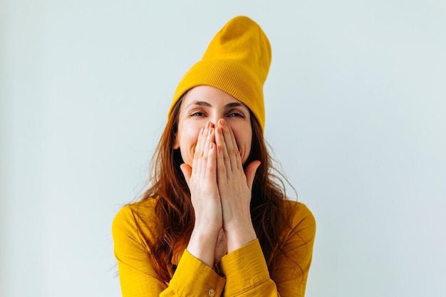 Smiling hipster girl teenage girl he covered his face with his hands with yellow hat on her head loo