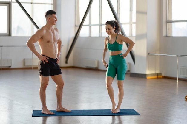 Smiling hispanic guy and girl doing sports in gym talking Fit young couple exercising