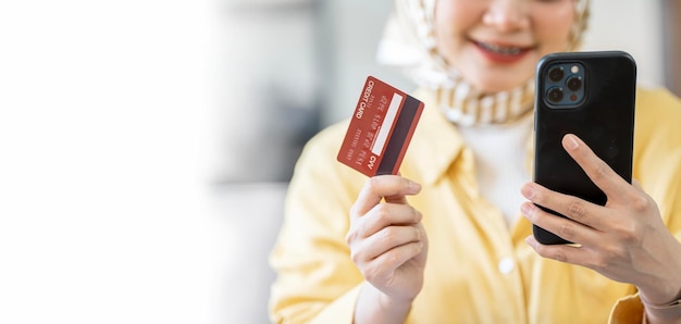 Smiling islamic girl in hijab make online banking use mobile phone enter credit card number for transaction happy muslim woman pay bank bills remotely easy electronic payment concept