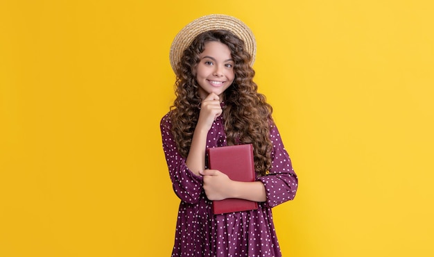 Smiling kid with frizz hair read book on yellow background