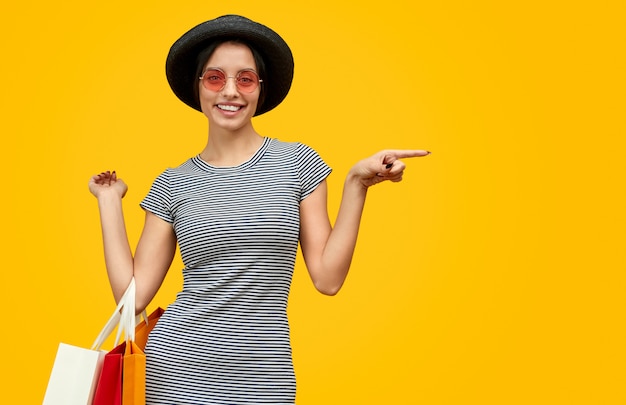 Smiling lady with paper bags pointing aside