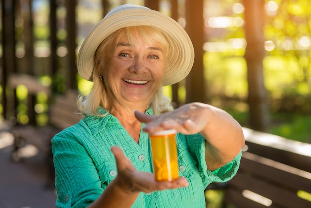 Smiling lady with pill bottle senior woman holds medicine good health and strong immunity most effec