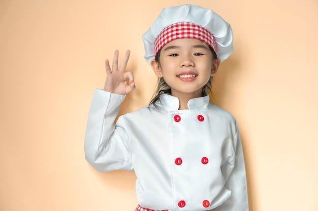 Smiling little asian chief with hat isolated on orange background