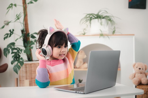 Smiling little Asian girl have a video call distant class with teacher using laptop, social distance during quarantine isolation during the Coronavirus