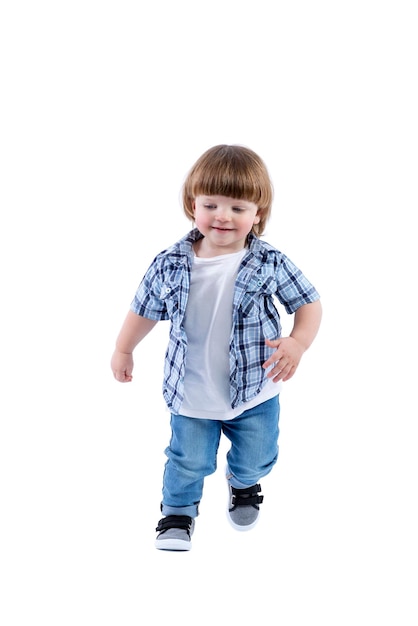 Smiling little boy 2 years old runs Child wearing a blue checkered shirt and a white Tshirt Activity energy and childlike spontaneity Full height Isolated on a white background Vertical