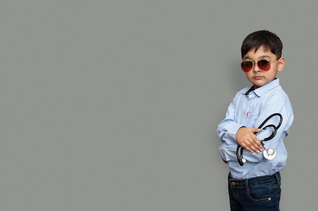 Smiling little boy with stethoscope and glasses isolated background with copy space