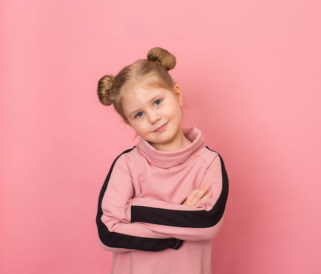 Photo smiling little girl portrai wearing two buns on pink background confident child with arms crossed