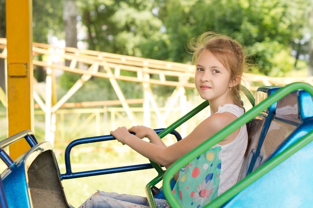 Smiling little girl sitting on a fairground ride