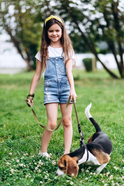 Smiling little girl standing with a dog and looking at the camera