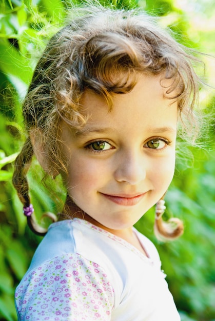 Smiling little girl with green leaves outdoors