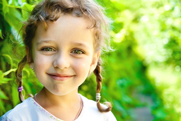 Smiling little girl with green leaves outdoors