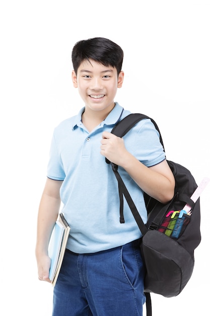 Smiling little student boy in blue polo t-shirt in with books and bag.