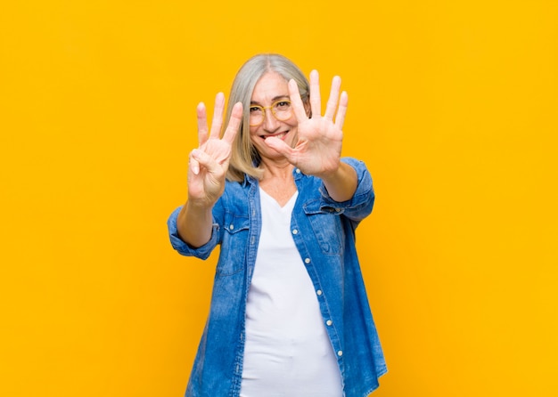 smiling and looking friendly, showing number eight or eighth with hand forward, counting down