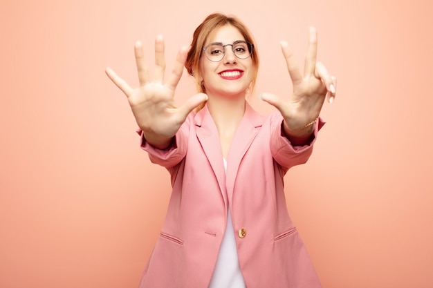 smiling and looking friendly, showing number eight or eighth with hand forward, counting down