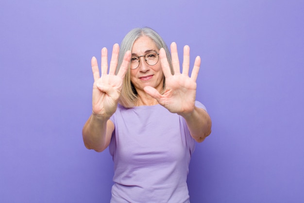 smiling and looking friendly, showing number nine or ninth with hand forward, counting down