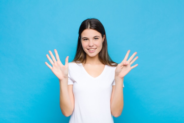 smiling and looking friendly, showing number nine or ninth with hand forward, counting down