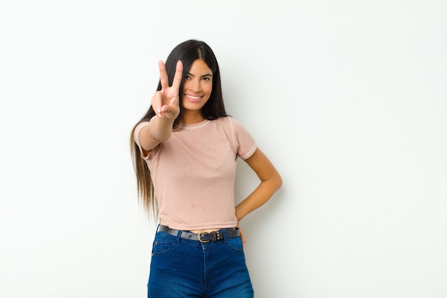 smiling and looking happy, carefree and positive, gesturing victory or peace with one hand