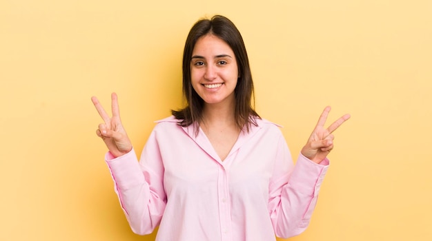 Smiling and looking happy friendly and satisfied gesturing victory or peace with both hands