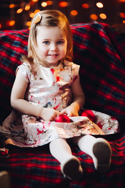 Smiling lovely baby girl in cute dress sitting on bench