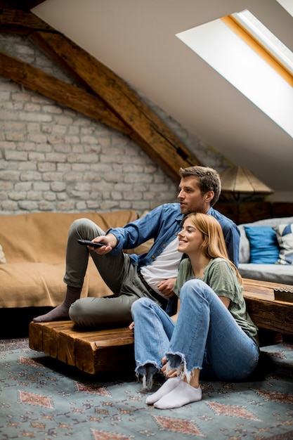 Smiling lovely young couple relaxing and watching TV at home