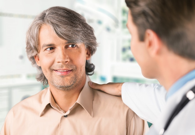 Smiling male patient with doctor on background