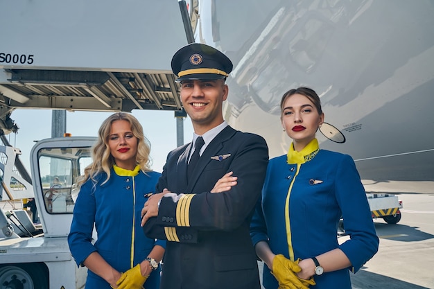 smiling male pilot and attractive flight attendants posing for the camera