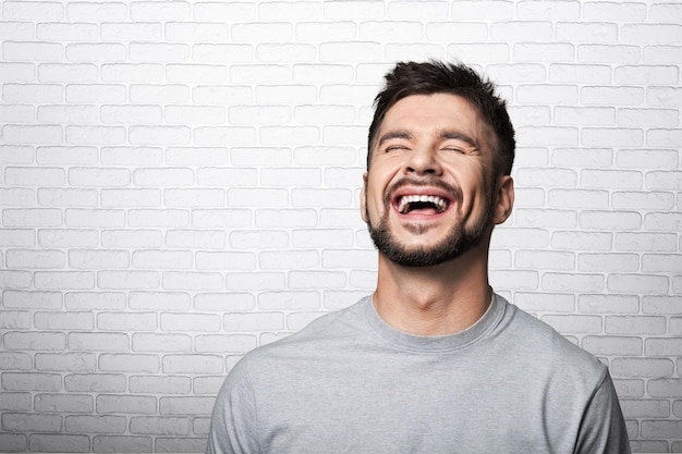 Smiling man in blank t-shirt, white grunge wall background