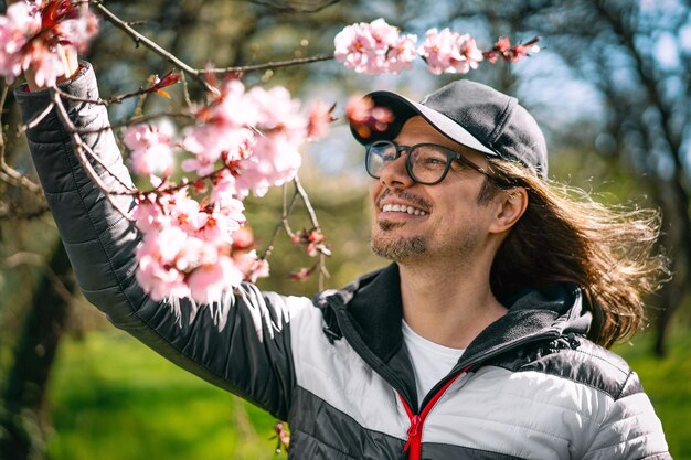 Photo smiling man by blooming tree in spring