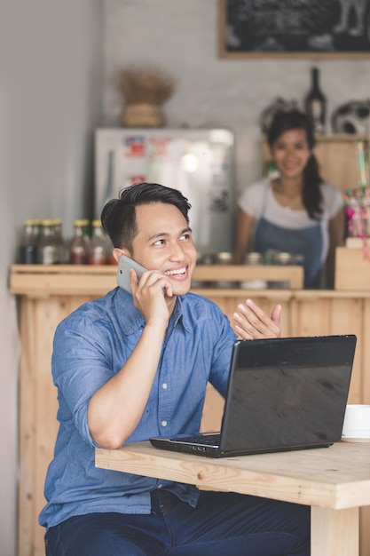 Smiling man calling by phone in the cafe