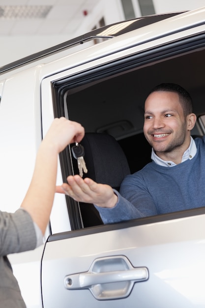 Photo smiling man in a car receiving a car key