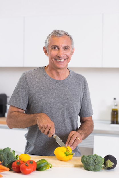 Smiling man cutting a yellow pepper