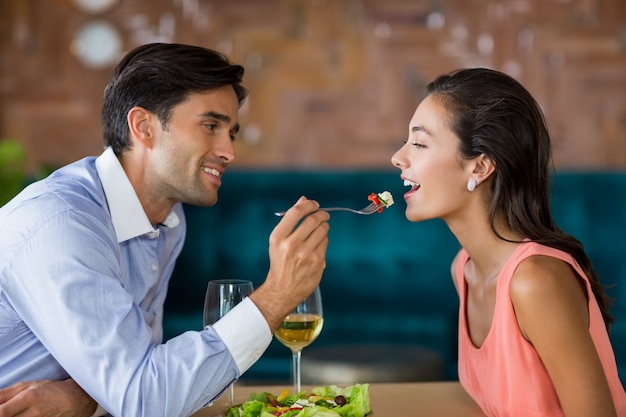 Smiling man feeding meal to woman