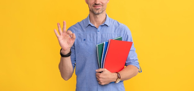 Smiling man hold school notebook or planner show ok gesture school